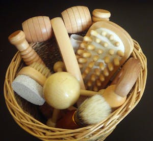 Top view of various wooden massage tools neatly arranged in a woven basket.